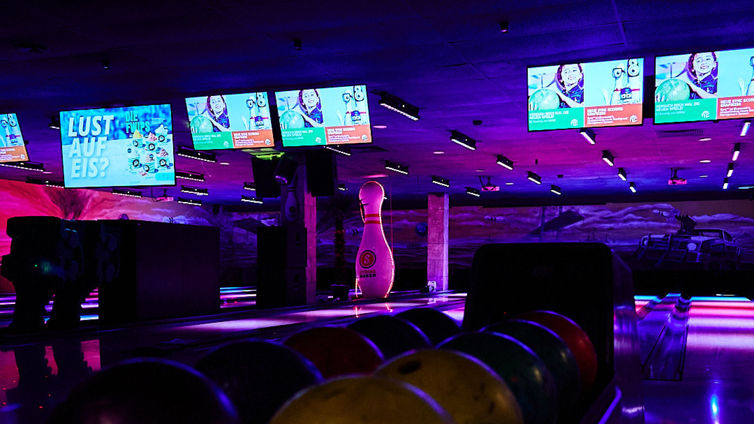 Bowlingkugeln vor den beleuchteten Bahnen im Blu Bowl Plochingen